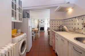 Een kleine keuken met een wasmachine, een magnetron en een spoelbak.