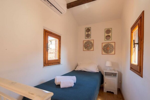 Une chambre à coucher comprenant un lit, une table de chevet, une fenêtre et des éléments décoratifs sur les murs.