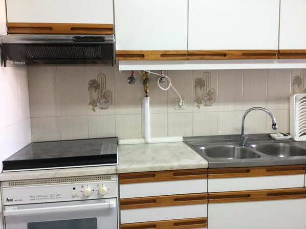 A kitchen with a stove, oven, sink, and decorative tiles.