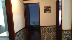 A hallway with patterned tile walls, a wooden door frame, and a small welcome sign on the wall. - APARTMENT LISBON - REBOLEIRA (metro / train) (Amadora)