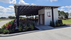 Un espace extérieur abrité avec des sièges, et en arrière-plan, un bâtiment blanc portant l’inscription « The Barn ».