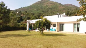 Un bâtiment moderne doté d’un toit plat et de grandes fenêtres, entouré d’une pelouse et d’arbres.