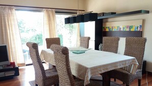 Un coin repas avec des chaises en osier et une table recouverte d’une nappe à rayures.
