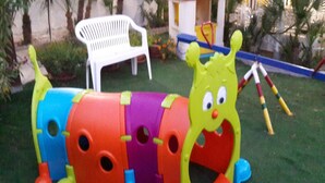 A colorful children's play structure with a slide, a white plastic chair, and a small building in the background. - cottage on the beach (Sciacca)