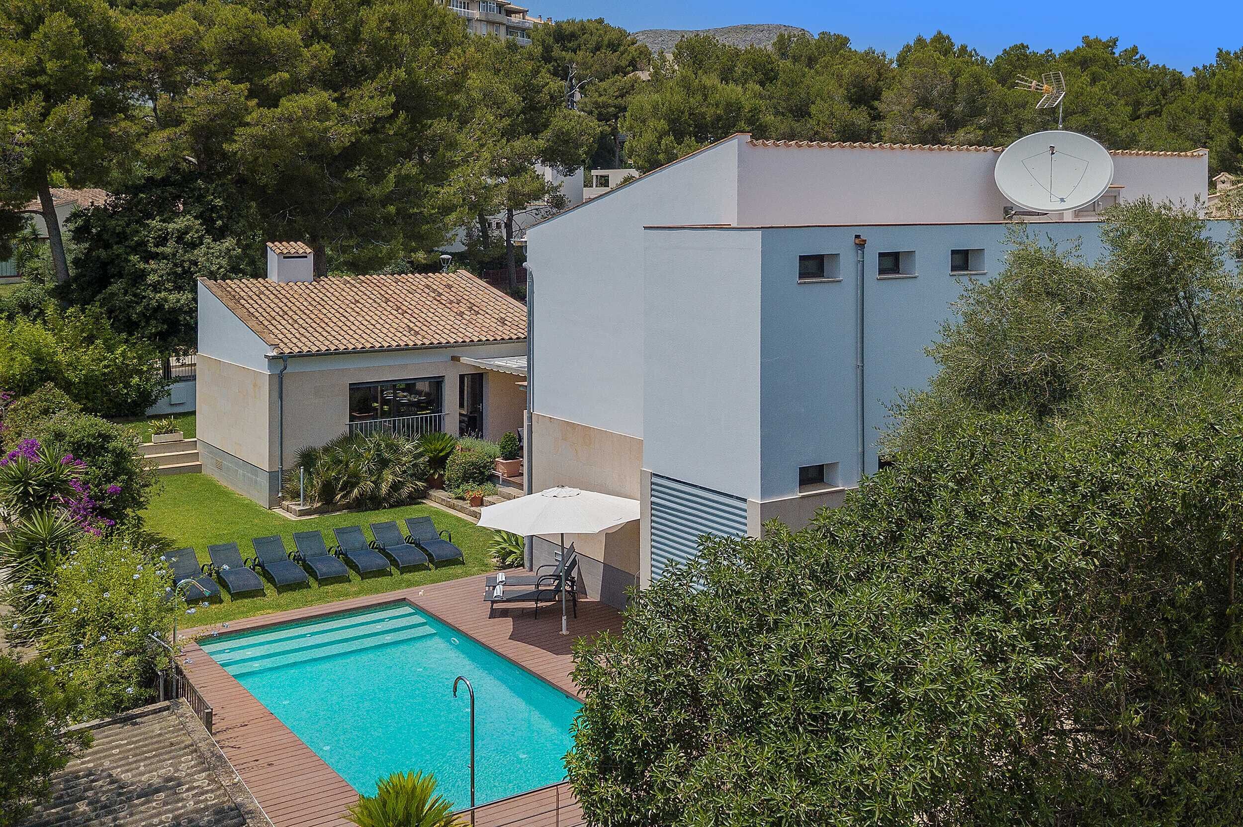 A modern building with a swimming pool, lounge chairs, and a satellite dish.