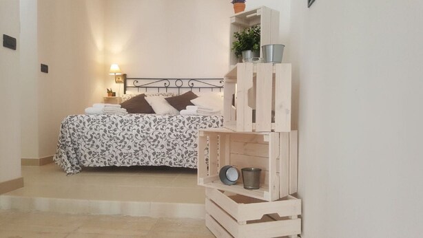 Un dormitorio con cama, mesita de noche, lámpara y mueble de almacenamiento de madera.
