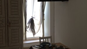 Un área de comedor con una mesa, sillas y un televisor montado en la pared.