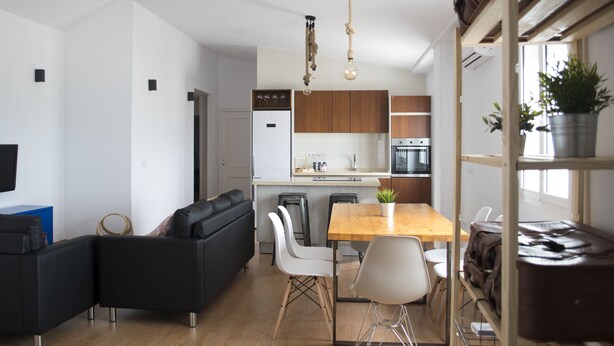 A modern kitchen with wooden cabinets, a built-in oven, and a dining area with a wooden table and chairs. - Atico73 Tourist Housing  (Medina-Sidonia)