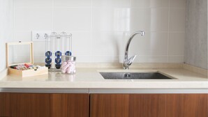 A kitchen with wooden cabinets, a white tiled backsplash, a stainless steel sink, and a wooden-framed mirror. - Atico73 Tourist Housing  (Medina-Sidonia)