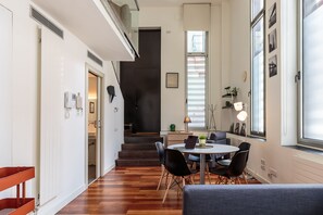 Una cocina moderna con comedor, piso de madera y una escalera que sube a un nivel superior.