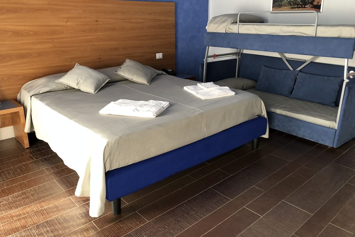 A double bed with a wooden headboard, a bunk bed, and a bedside table.