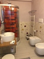 Ein Badezimmer mit Duschkabine, Waschbecken, Toilette und Handtuchhalter.