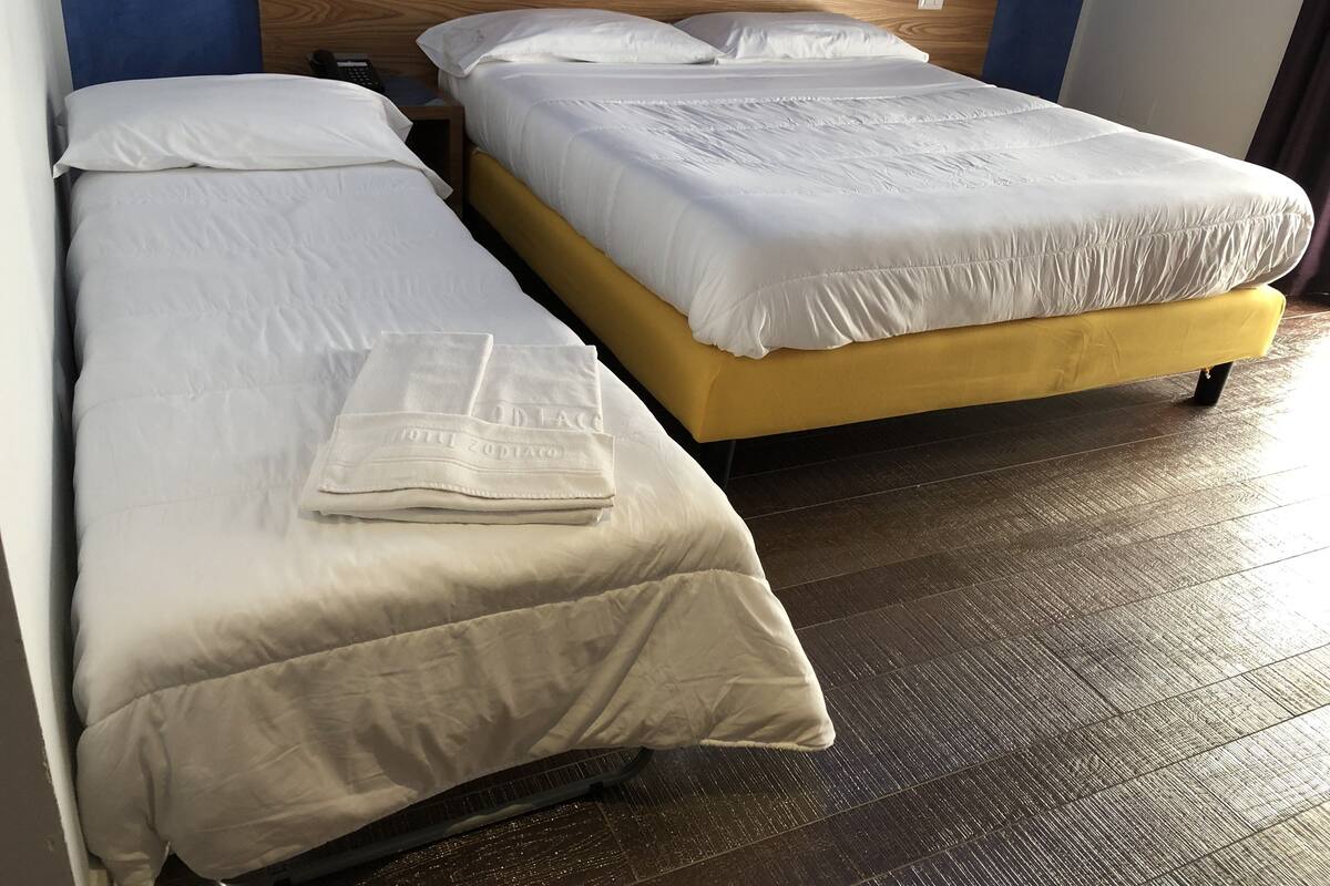 Two single beds with white bedding, a wooden headboard, and a wooden floor.