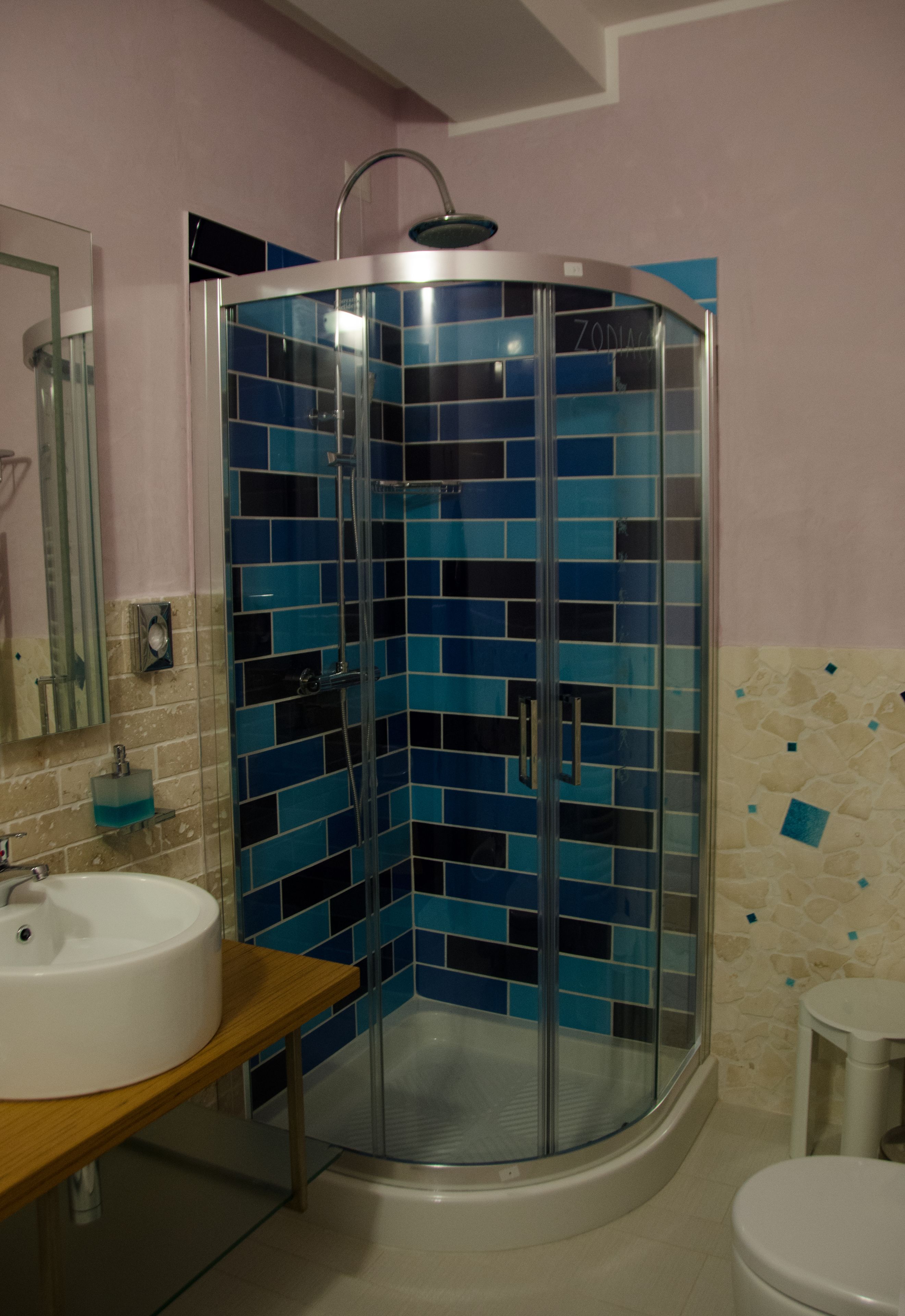 A bathroom with a glass-enclosed shower, a sink, and a toilet.