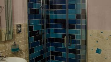 Un baño con ducha envuelta en vidrio, lavamanos e inodoro.