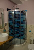 Un baño con ducha envuelta en vidrio, lavamanos e inodoro.