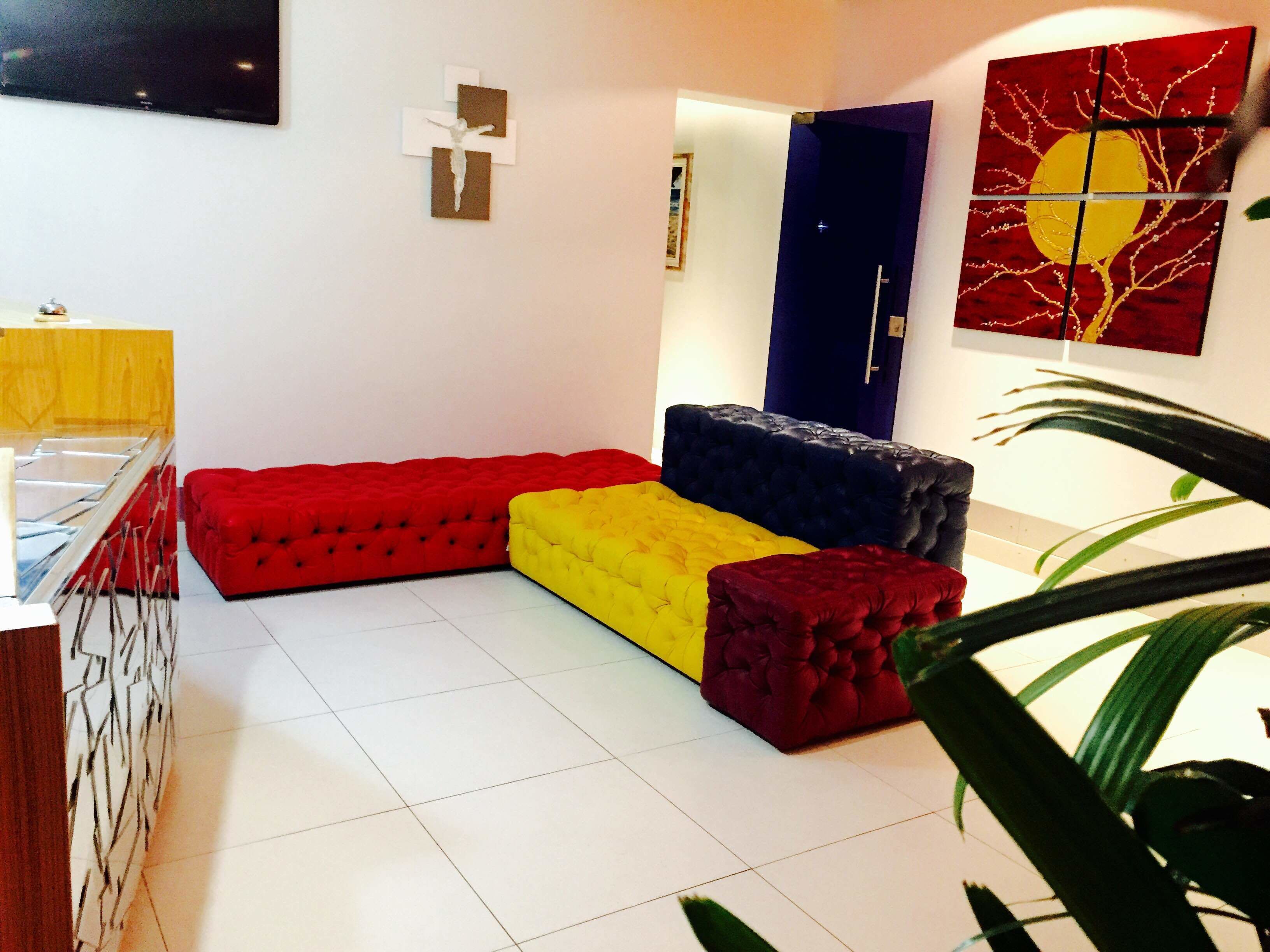 Un soggiorno moderno con un divano componibile rosso, giallo e blu, una televisione a schermo piatto e una porta con un dipinto astratto rosso e giallo.