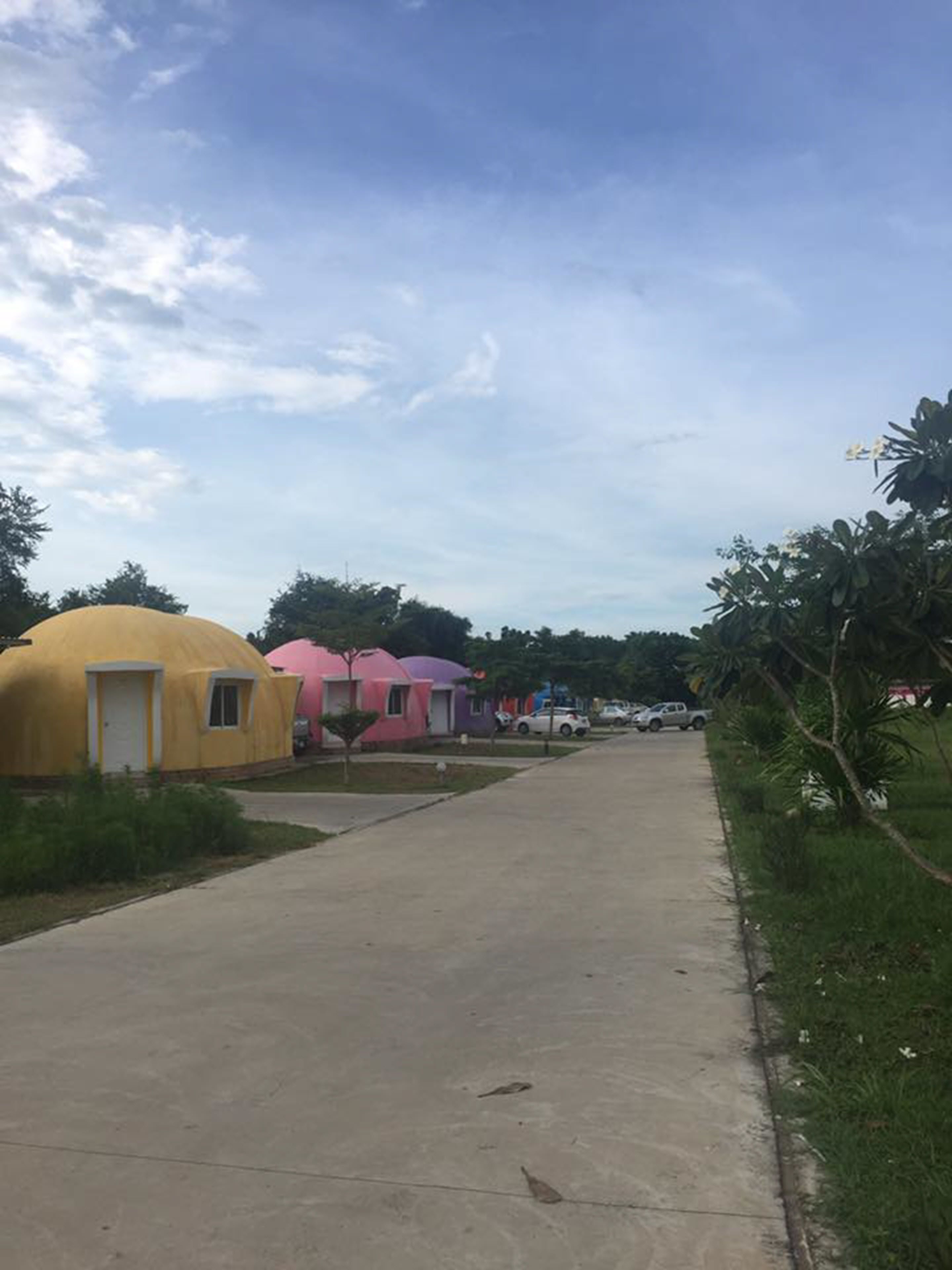 A row of colorful yurts along a paved path with a clear sky above.