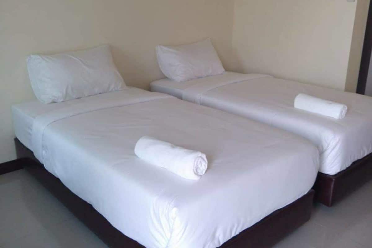 A hotel room with two single beds, each with white linens and pillows, and a dark wooden headboard.