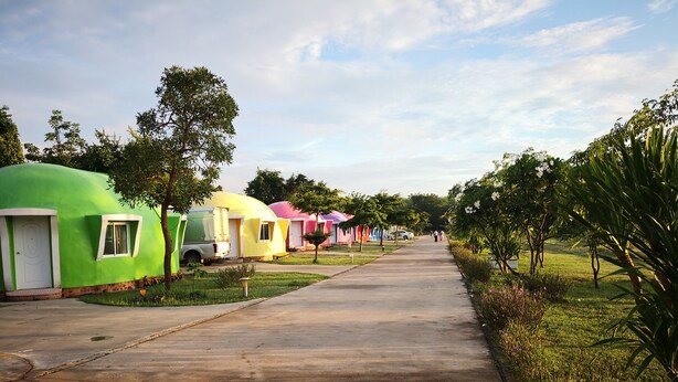 A row of colorful, dome-shaped cabins with a concrete pathway leading through them. - Eskimo Resort (Phetchabun)
