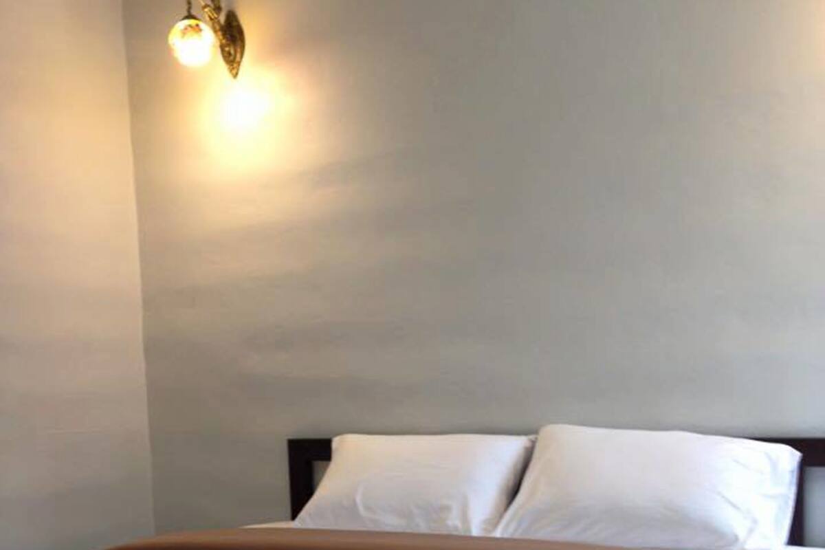 A neatly made bed with a brown bedspread and two rolled white towels placed on it.