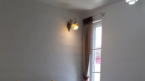 A neatly made bed with white and yellow pillows, a rolled towel, and a wall-mounted light fixture. - Eskimo Resort (Phetchabun)