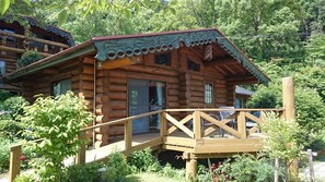 A wooden log cabin with a wooden deck and a staircase leading to the entrance.