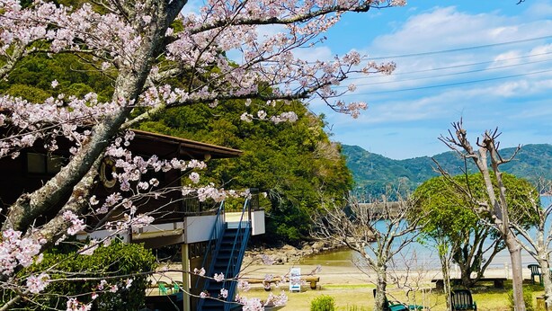 A traditional Japanese-style building with a wooden exterior, a staircase leading to the upper floor, and a view of a lake with a mountain in the background. - Pension Shishikui (Kaiyo)