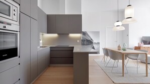 A modern kitchen with built-in appliances, a central island, and a dining area with a table and chairs. - La Dolce Vita by FeelFree Rentals (San Sebastián)