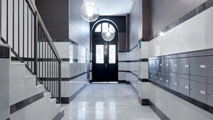 A hallway with marble floors, a staircase with metal railings, and lockers on one side. - La Dolce Vita by FeelFree Rentals (San Sebastián)