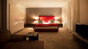 Una habitación de hotel moderna con una cama grande, televisión, sofá y escritorio.
