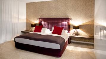 A modern bedroom with a large bed, two bedside tables, and a headboard with built-in lighting.