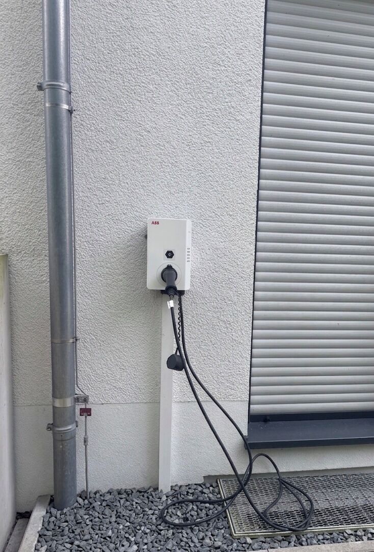 A utility box with a cable connected to a metal pipe and a window with closed blinds.