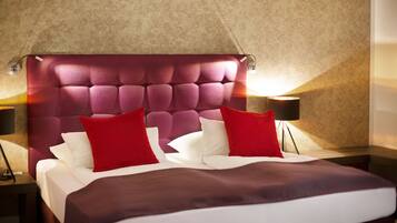 A hotel room with a tufted headboard, a bed with white and red bedding, and two bedside lamps.