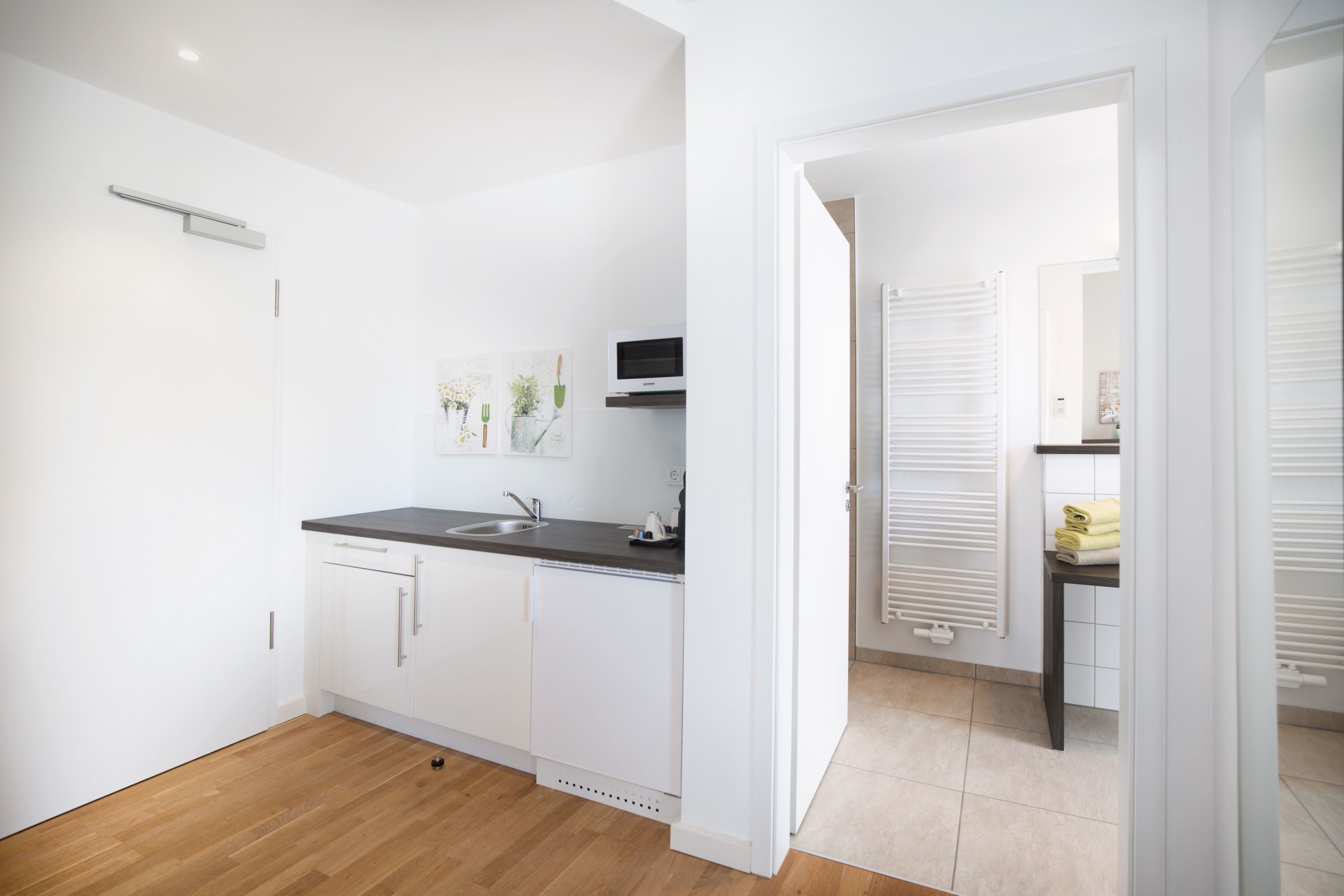 A modern kitchen with white cabinets, a black countertop, and a built-in microwave.