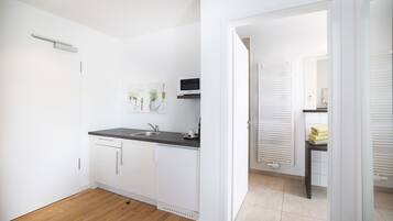 A modern kitchen with white cabinets, a black countertop, and a built-in microwave.
