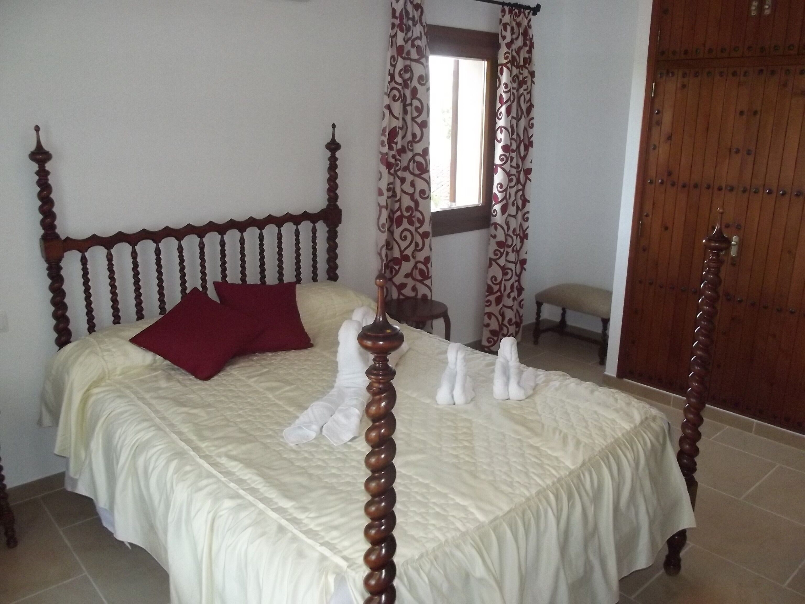 Un lit à baldaquin avec une tête de lit en bois, un oreiller rouge et un couvre-lit blanc.