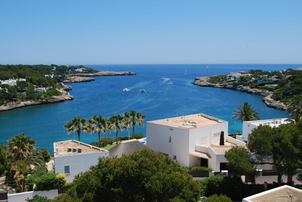 Vista costera con edificios, un puerto deportivo y aguas azul turquesa.