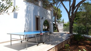 An outdoor table tennis table set up against a white building with arched doorways and a balcony. - EXCLUSIVE VILLA WITH PRIVATE POOL, JUST 1 MINUTE FROM CALÓ DES POU BEACH (Cala D'or/Santanyi)