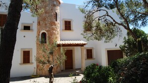 A white building with a stone tower, wooden shutters, and a tiled roof. - EXCLUSIVE VILLA WITH PRIVATE POOL, JUST 1 MINUTE FROM CALÓ DES POU BEACH (Cala D'or/Santanyi)