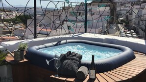 Een hottub op een houten terras met uitzicht op een stadsbeeld.