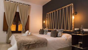 Habitación de hotel con una cama grande, una mesita de noche con lámpara y una lámpara de pared.