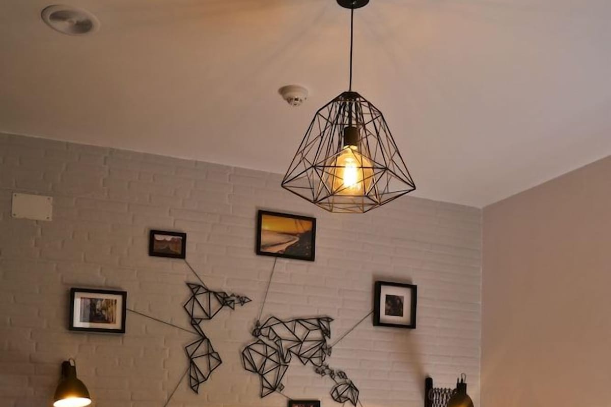 Une chambre à coucher comprenant un lit, deux tables de chevet, un luminaire fixé au mur et une œuvre d’art murale aux motifs géométriques.