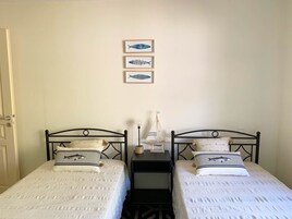 Una habitación con dos camas, una mesita de noche y decoración de peces en la pared.