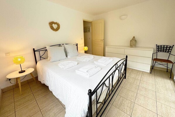 A bedroom with a bed, bedside lamps, a desk, a chair, and a small statue on the dresser. - Villas La Clairière aux Chevreuils (Moliets-et-Maa)