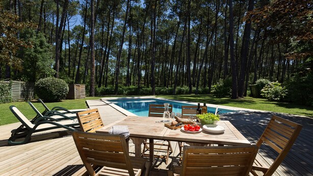 A wooden deck with a pool table, chairs, and a bottle of wine. - Villas La Clairière aux Chevreuils (Moliets-et-Maa)