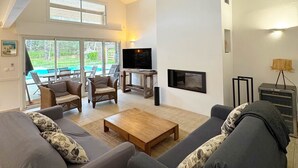 A living room with a sofa, chairs, a coffee table, a TV, and a fireplace. - Villas La Clairière aux Chevreuils (Moliets-et-Maa)