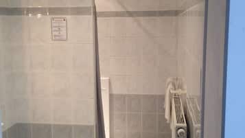 A shower area with tiled walls, a shower curtain, a towel rack, and a waste basket.