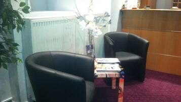 A room with two black leather chairs, a small table with magazines, and a radiator.
