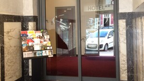 A hotel entrance with a glass door, a marble floor, and a display of brochures.